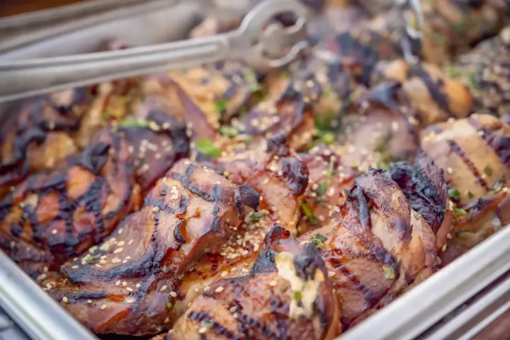Grilled meat slices with sesame seeds in a tray.